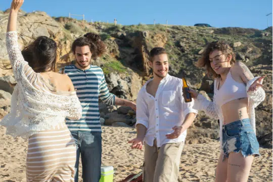 grupo de amigos y parejas jóvenes en la playa bailando