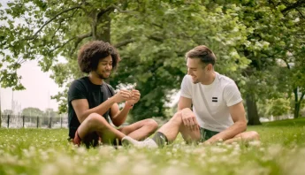 Dos personas jóvenes sentadas sobre el pasto en un parque